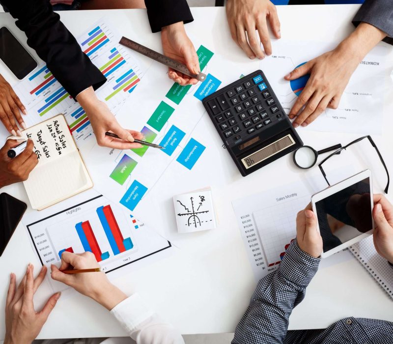 Picture of businessmen's hands on white table with documents, coffee and drafts