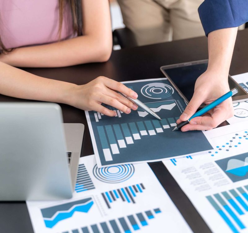 close up hand of marketing manager employee pointing at business document during discussion at meeting room , Notebook on wood table - Business concept