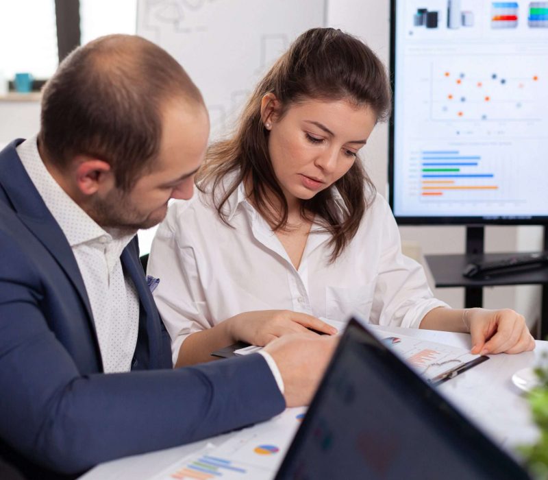 Colleagues of startup business discussing looking at documents in company board brainstorming conference room checking graphs and charts. Financial analysis during briefing.