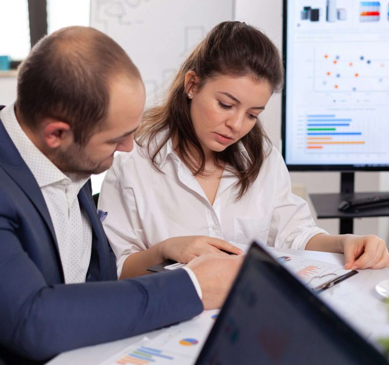 Colleagues of startup business discussing looking at documents in company board brainstorming conference room checking graphs and charts. Financial analysis during briefing.