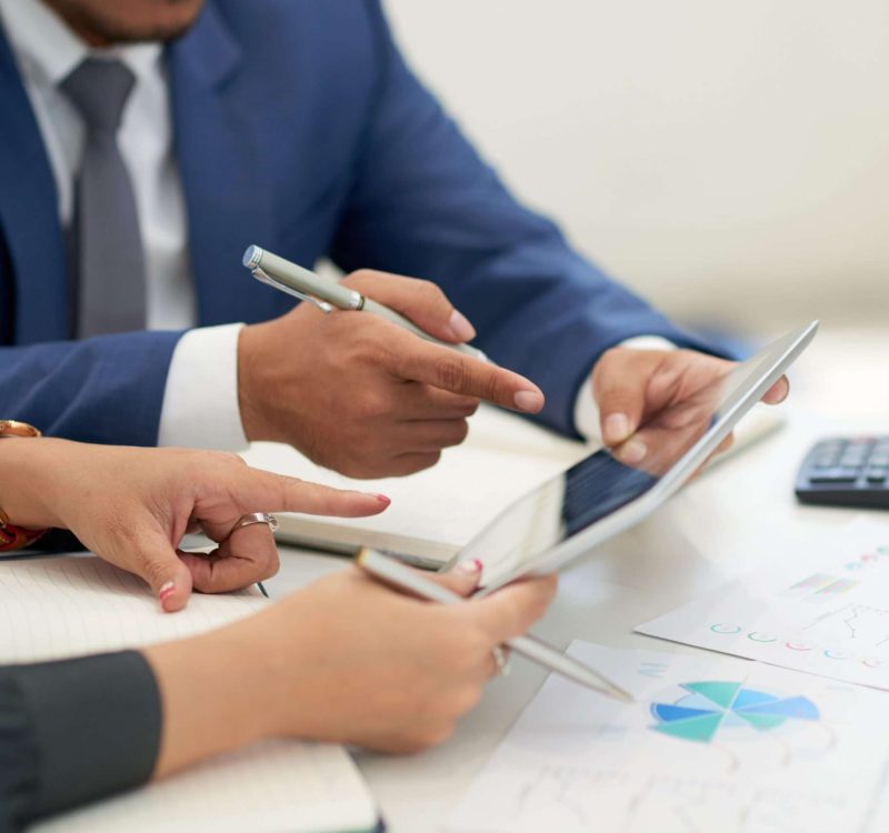 unrecognizable-business-people-sitting-meeting-with-charts-looking-pointing-tablet