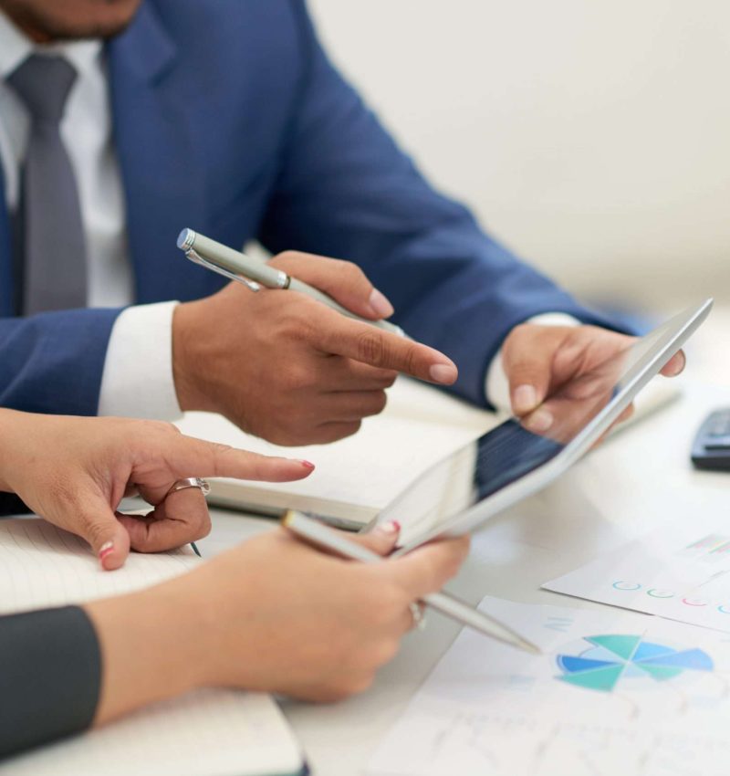 unrecognizable-business-people-sitting-meeting-with-charts-looking-pointing-tablet